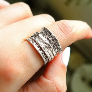 Vintage silver wide spinner ring with floral relief textures for women in close-up shot