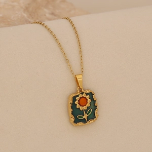 Gros plan détaillé d'un pendentif tournesol vintage avec émail vert sur chaîne dorée