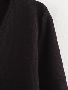 Nahaufnahme von schwarzem Strickstoff mit Schulternaht und V-Ausschnitt-Detail