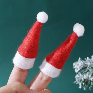 Close-up of mini red and white knitted Christmas hats worn on fingers with festive decor