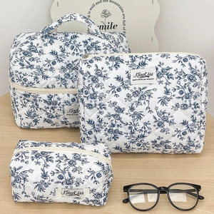 Three-piece floral quilted cotton cosmetic bag set on a light wood background