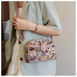 Detail of pink canvas crossbody bag featuring cute bear patterns and leather strap
