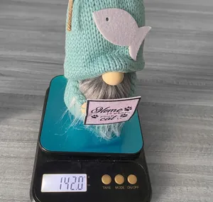 Detail shot of a knitted gnome doll on an electronic scale showing product weight