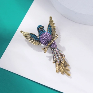 Close-up of vintage eagle brooch with blue and purple crystals on gold alloy