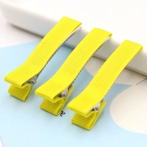 Close-up of three yellow fabric-wrapped duckbill hair clips showing detailed texture
