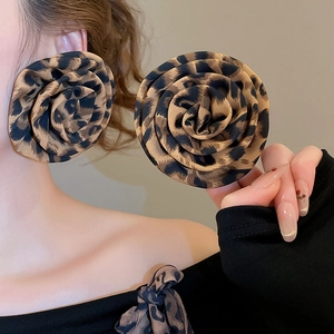 Close-up of oversized leopard print fabric flower earrings on model and hand