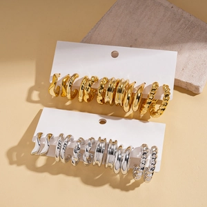 Set of 12 geometric hoop earrings in gold and silver finish on modern stone display