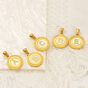 Golden round alphabet pendants with white inlay and twisted rope edges on marble background