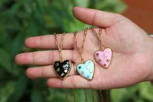 Detailed close-up of heart pendants with gold stars on gold paperclip chains