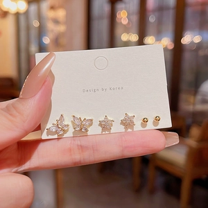 Detailed view of a gold earring set featuring butterfly, star, and round stud designs