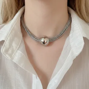 Multi-layer silver chain necklace featuring a large polished metal ball pendant on a model