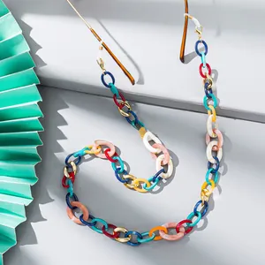 Macro shot of colorful acrylic resin eyeglass chain with gold hooks on a grey background