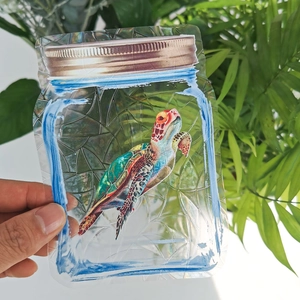 Detail of holographic jar-shaped PVC bag with rainbow prism sea turtle illustration