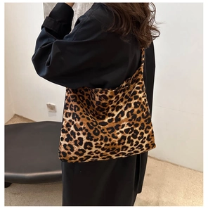 Détail du sac bandoulière à motif léopard marron porté sur une tenue noire
