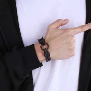 Close-up of a double-layered black wolf head bracelet on a male wrist with ring clasp detail