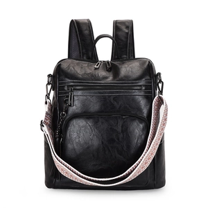 Detail of black faux leather backpack featuring a textured finish and colorful woven strap