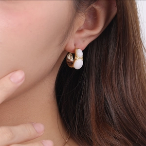 Detail of C-shaped gold earring with white stones on model showing modern jewelry design