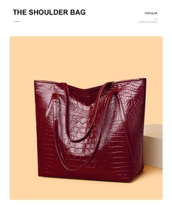 Detail of burgundy crocodile pattern tote bag with polished faux leather finish