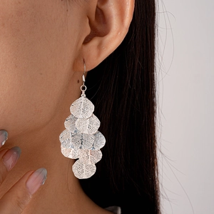 Close-up of silver hollowed leaf tassel earrings worn by a model in a modern style
