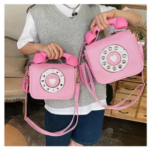 Detail of pink vintage telephone-shaped crossbody bag featuring retro rotary dial and handset handle