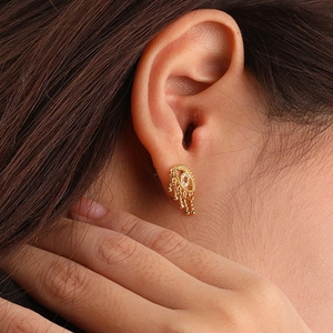Close-up of S925 silver eye hoop earring with crystal inlay and golden beaded tassels