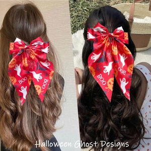 Detail of red Halloween bow hair clip with ghost pumpkin prints and long streamers