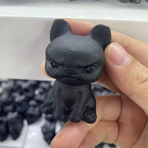 Handheld matte black obsidian French Bulldog puppy figurine showing detailed craftsmanship