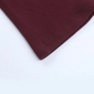 Detail of burgundy knitted dress showing clean hemline stitching and fabric texture