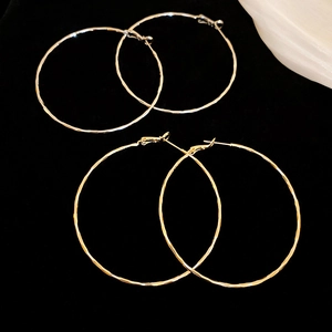 Detail of large gold and silver hoop earrings with a handcrafted hammered texture