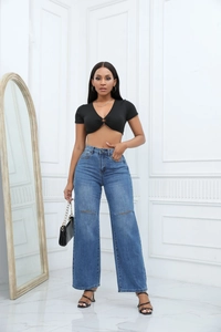 Detail of high waisted wide leg distressed blue jeans with ripped knees and loose fit