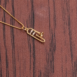 Makroaufnahme des goldenen Trompeten-Anhängers mit Zirkon auf braunem Leder