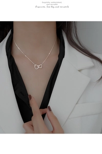 Detail shot of a silver double interlocking heart necklace on a model's collarbone