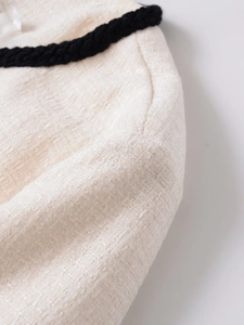 Détail macro du tissu en tweed crème avec bordure tressée noire décorative et texture