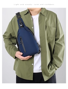Detail of navy blue crossbody chest bag with adjustable strap and zip pockets on model