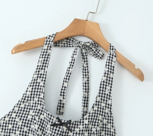 Detail of floral embroidery on a black and white plaid halter dress with a black bow