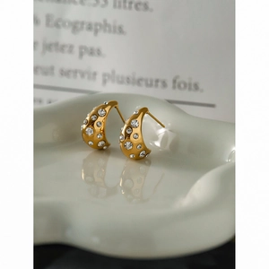 Macro detail of 18k gold stainless steel hoop earrings with sparkling rhinestones on ceramic