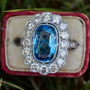 Macro view of vintage silver cluster ring with large oval blue sapphire in a red jewelry box