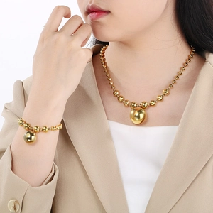 Close-up of golden titanium steel ball pendant necklace and bracelet set on a model