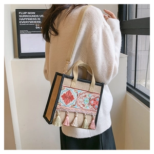 Detailed embroidery on a linen tote bag with colorful tassels and crossbody strap