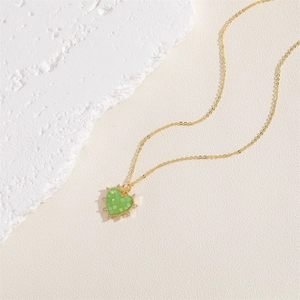 Détail du pendentif cœur à carreaux verts sur collier plaqué or 14K avec zircons
