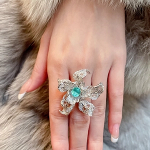 Macro shot of silver flower ring featuring turquoise stone and pavé diamonds on finger