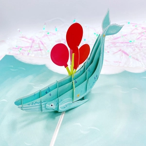 Close-up of 3D pop-up birthday card featuring a blue whale and red balloons