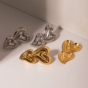 Detailed view of textured 18K gold and silver double heart-shaped pendant earrings