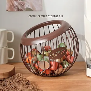 Brown metal coffee capsule storage basket with COFFEE cutout on a wooden tabletop