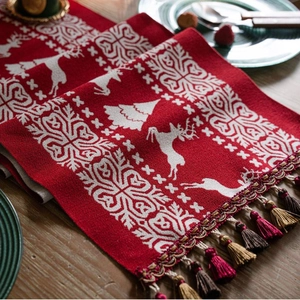 Red Christmas jacquard table runner with white reindeer patterns and colorful tassels