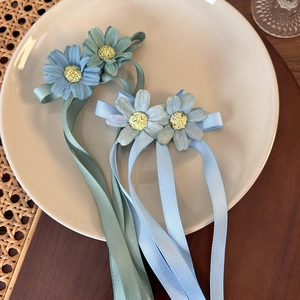 Detailed view of handmade daisy hair clips with light blue and mint green ribbons