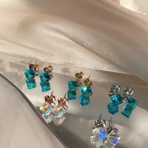 Elegant crystal cube stud earrings in blue and white on silk fabric background