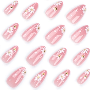 Short almond press-on nails with bee and daisy designs in a minimalist 16-piece set