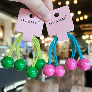 Detail of dual ball cherry style elastic hair ties in green and pink contrast colors