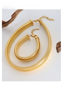 Detail of 18K gold plated necklace and bracelet set with ribbed texture on wood block